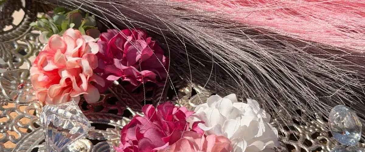 Roze en rode zijden bloemen met veren en glazen accenten op een zilveren onderzetter