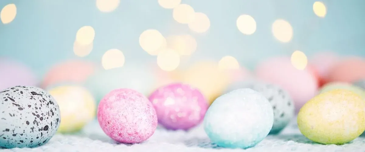 Pastelkleurige gespikkelde paaseieren voor een lichtblauwe achtergrond