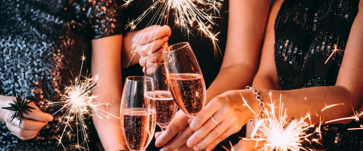 Handen die klinken met champagneglazen tussen brandende sterretjes