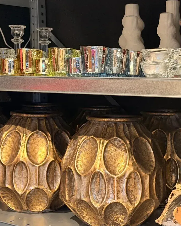 Rekken met glaswerk, kandelaars en gouden vazen in het atelier