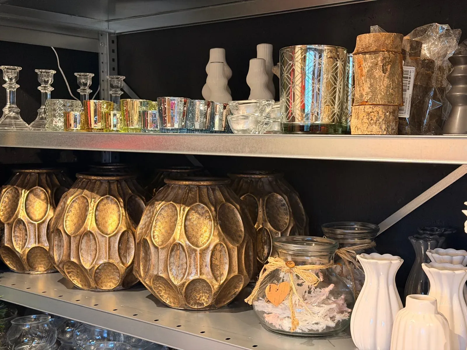 Rekken met glaswerk, kandelaars en gouden vazen in het atelier