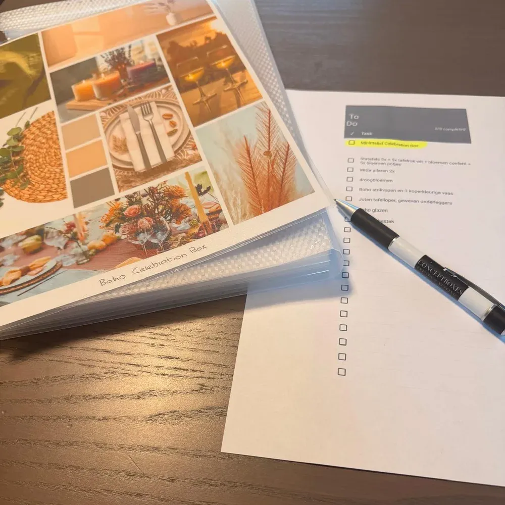 De moodboardmap van de Boho Celebration Box naast een materiaallijst met pen